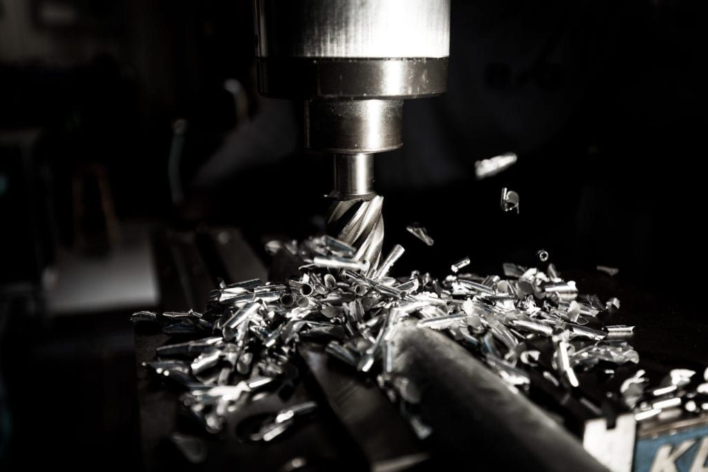 A CNC machine spindle cutting metal parts with shavings flying
