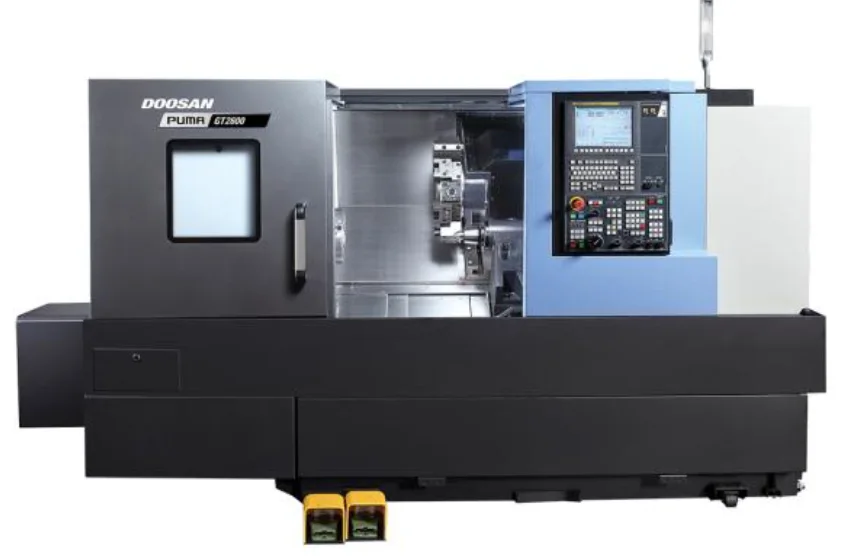 A Doosan Puma CNC lathe with a blue control panel and a large viewing window in the door